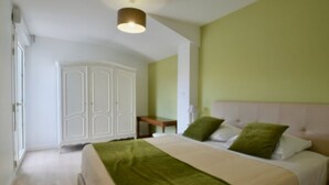 A bedroom with a bed, a wardrobe, a bedside table, and a lamp. - Gîtes Monplaisir - Maison Guyenne (Marmande)