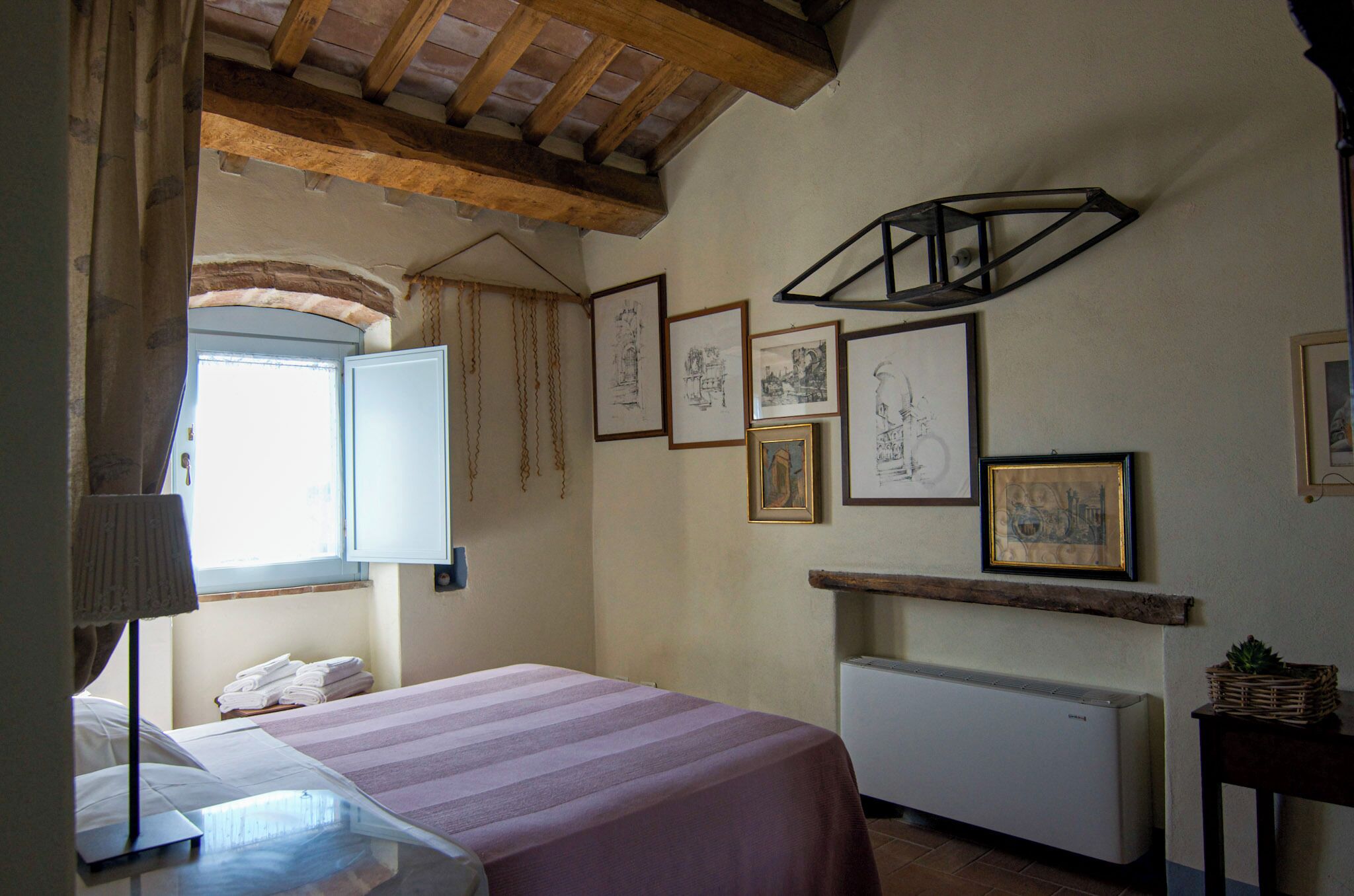 A bedroom with a bed, a radiator, and framed artwork on the wall.