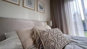 A bed with a patterned throw pillow, a headboard, and framed artwork on the wall. - Nordic Zen 2BR Beach House • Bali-Inspired Calm (Vārzas)