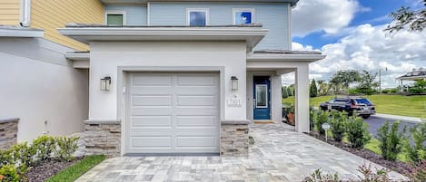 A modern two-story house with a white garage door, a blue front door, and a stone accent wall.