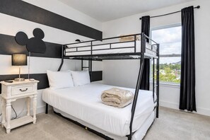 A bunk bed room with a nightstand, a Mickey Mouse cutout, and a view of the outdoors. - Reunion 3BR Villa Near Disney + Pool Access (Kissimmee)