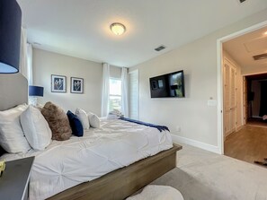 Una camera da letto con un letto, una TV a parete e una porta che dà su un'altra stanza.