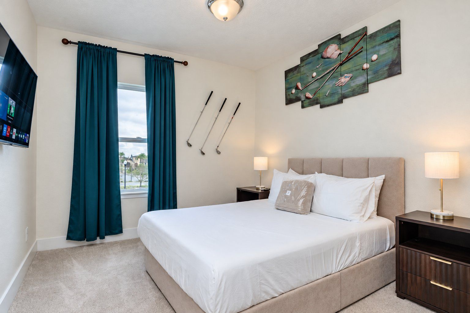 A hotel room with a bed, two bedside tables, a TV, a window with curtains, and a painting on the wall.