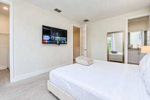 A hotel room with a large bed, a flat-screen TV mounted on the wall, a walk-in closet, and a bathroom visible through an open door. - Reunion 3BR Villa Near Disney + Pool Access (Kissimmee)