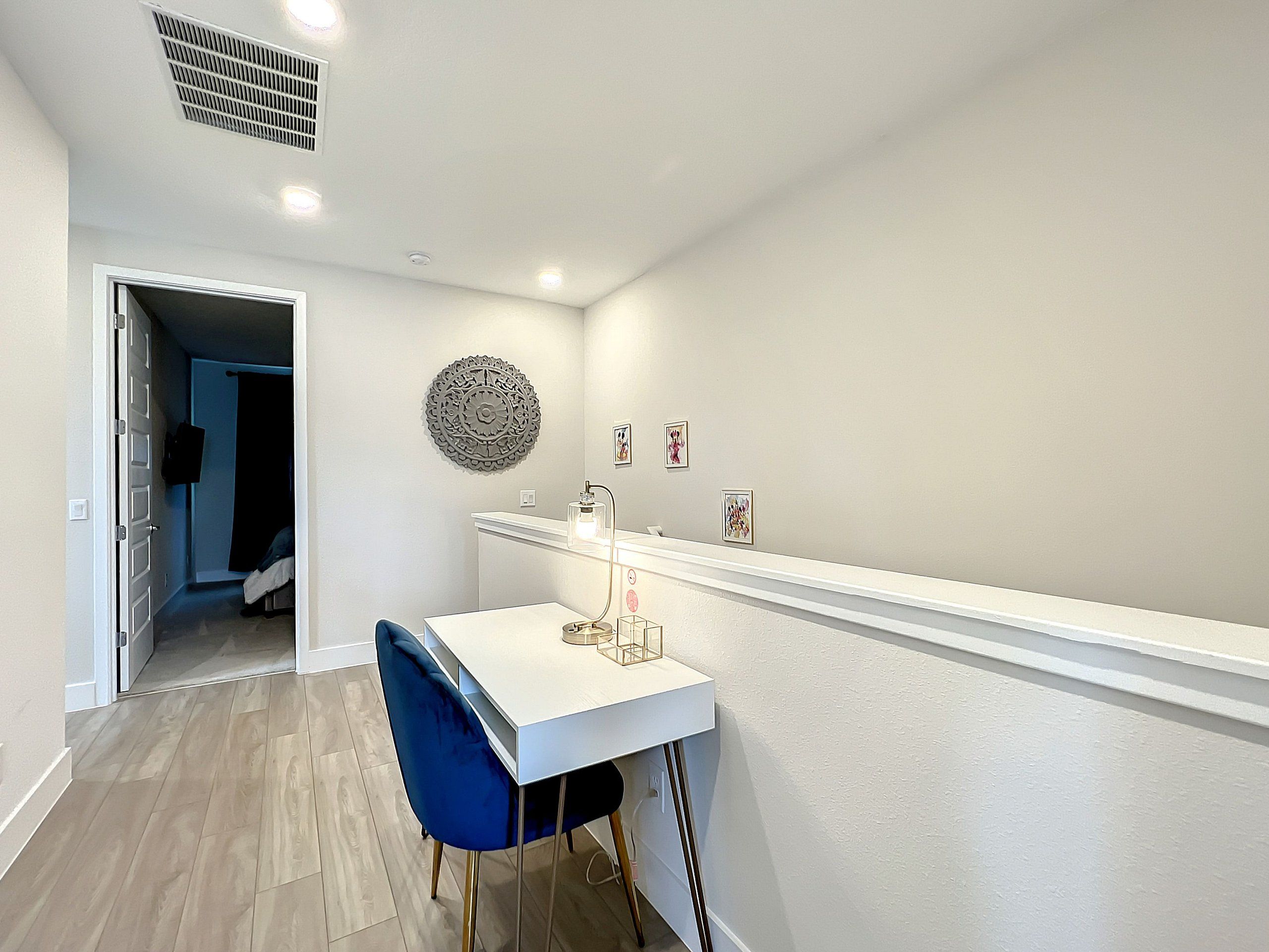 A modern room with a white desk, blue chair, and a decorative wall piece.