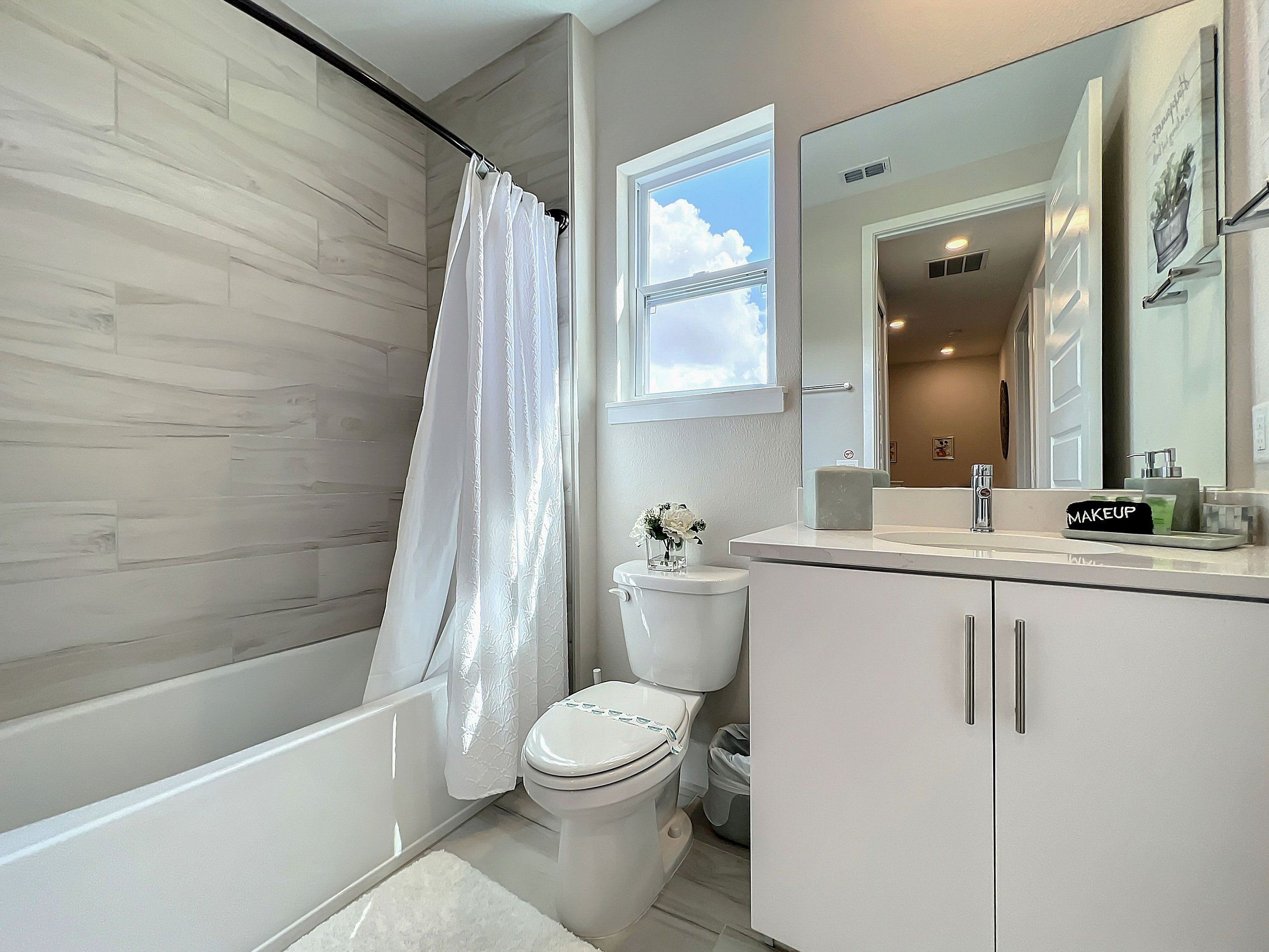 A modern bathroom with a bathtub, toilet, and vanity.
