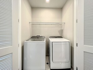 A laundry room with two stacked washers and dryers, a metal drying rack, and a vented ceiling. - Reunion 3BR Villa Near Disney + Pool Access (Kissimmee)