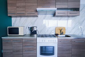Una cocina moderna con armarios de madera, microondas, cafetera, estufa y horno.