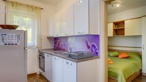 Cozinha compacta com armários brancos, forno embutido e pia.