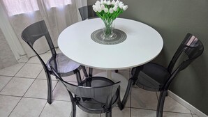 A round white table with a glass vase of white flowers, surrounded by four black chairs. - RHO FIERA FLAT- 100 M FROM THE METRO (Pero)