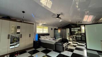 A bedroom with a checkered floor, a bed, a wardrobe, and a ceiling fan.