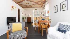 Un soggiorno con TV, divano a fantasia, tavolo da pranzo e sedie.
