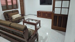 Un salon avec un canapé, une table basse, un meuble et un téléviseur fixé au mur.