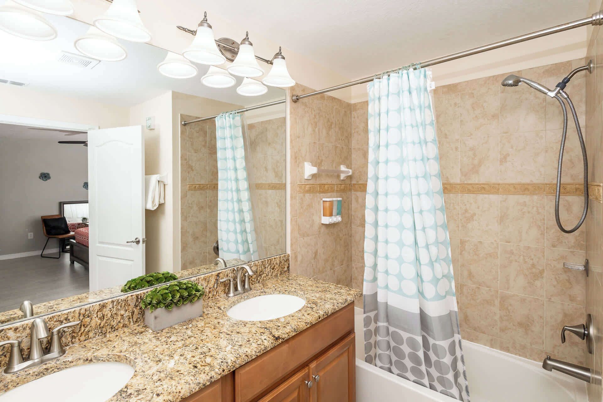 A bathroom with two sinks, a shower, and a mirror.