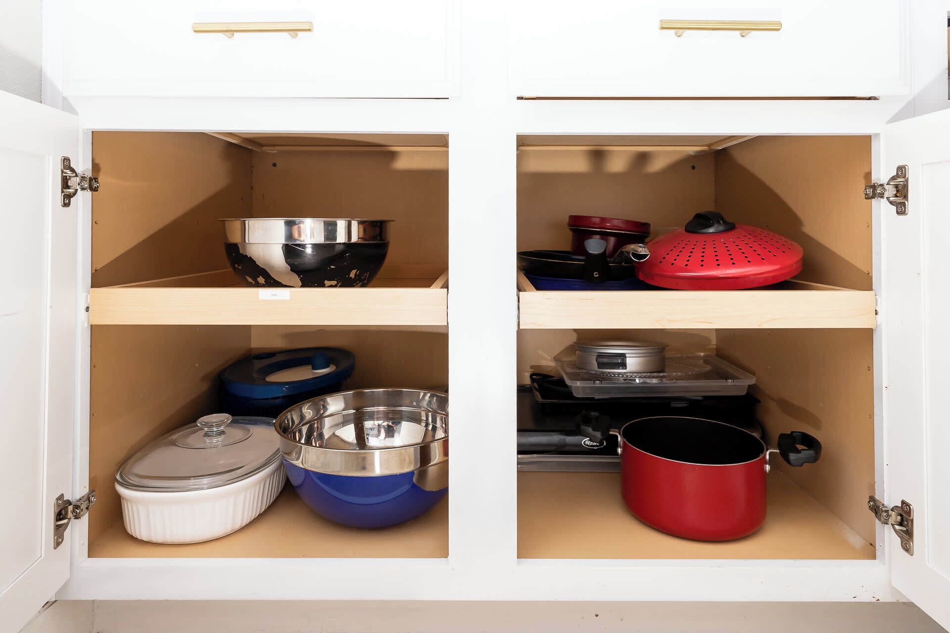 A kitchen cabinet with two shelves, each containing various kitchenware items.
