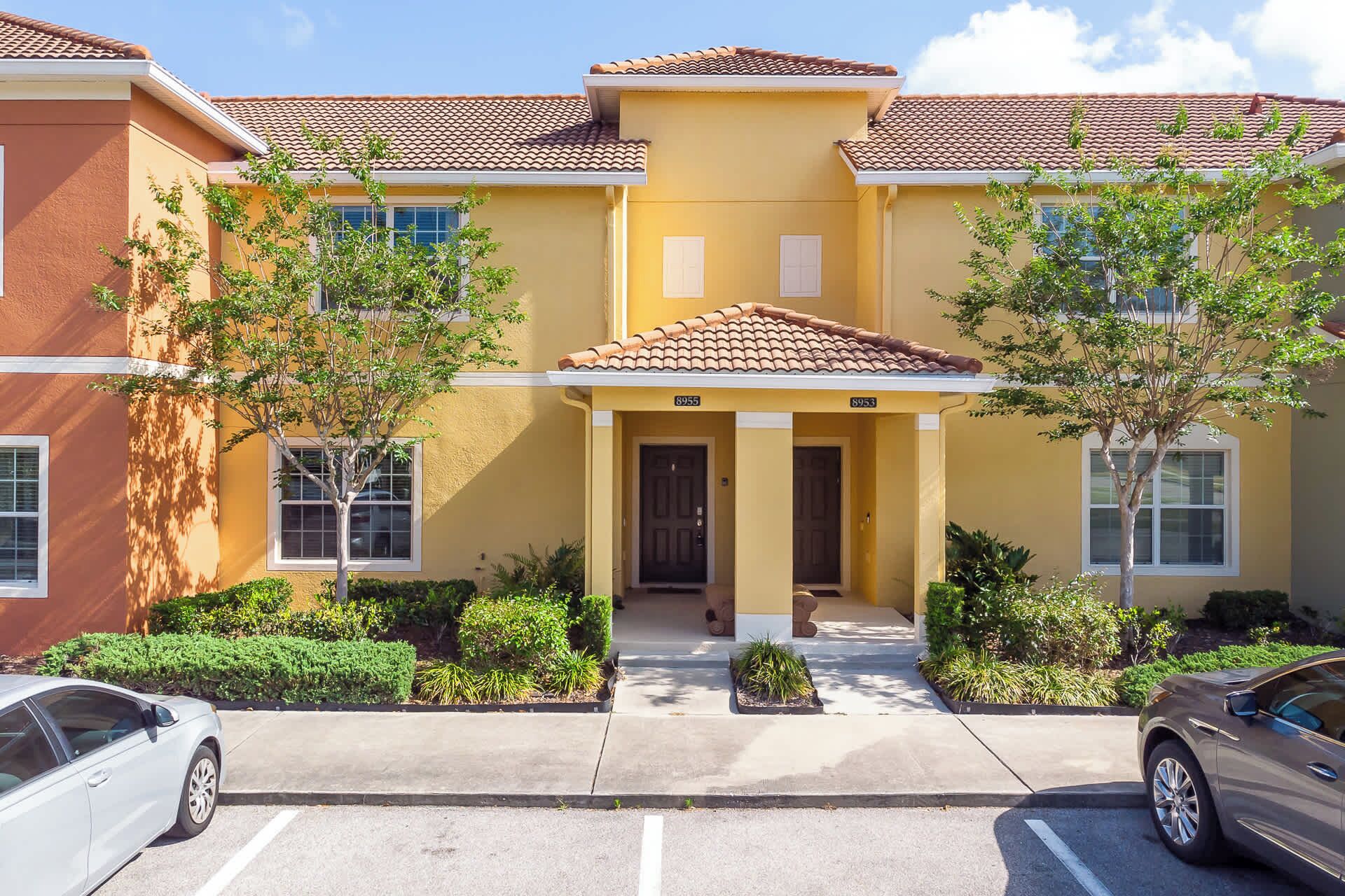 A multi-story building with a yellow facade, a tiled roof, and a central entrance with a porch.