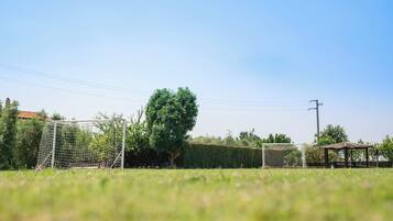 A soccer field with a goalpost, a tree, and a gazebo.