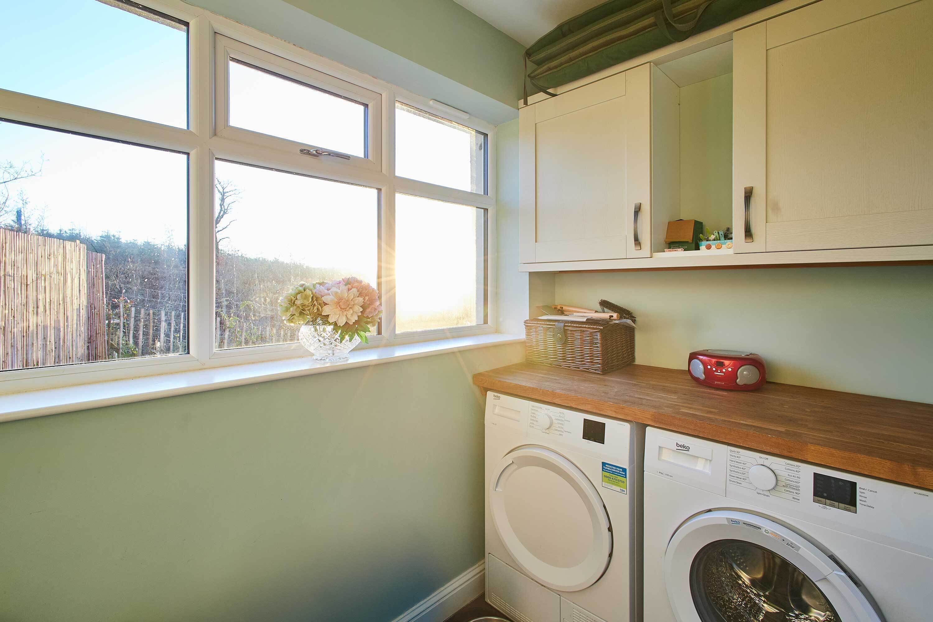 A laundry room with a washing machine, a dryer, and a window with a view of a fence.