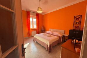 A bedroom with a bed, a bedside table, a lamp, and a radiator. - GuestHost - A comfortable and welcoming 70 square meters apartment, perfect for four people, located on the third floor of a building (NO elevator).The property is located in a quiet area and well-connected to the city center, reachable in about 20 minut (Alessandria)