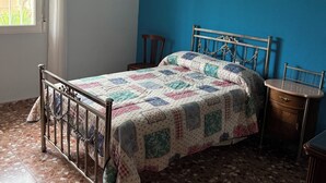 A bedroom with a bed, a chandelier, a window, and a blue wall.