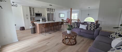 Un espacio de estar moderno con cocina, comedor y zona de estar con sofá y sillones.