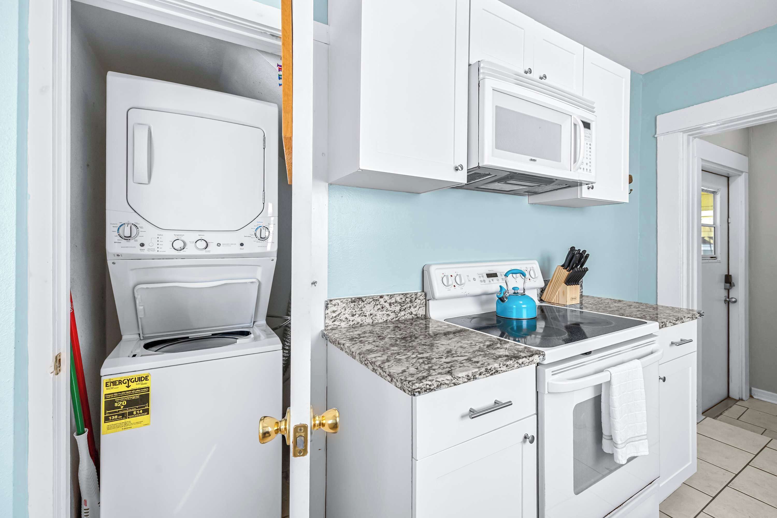 A kitchen with a washing machine, microwave, and stove.