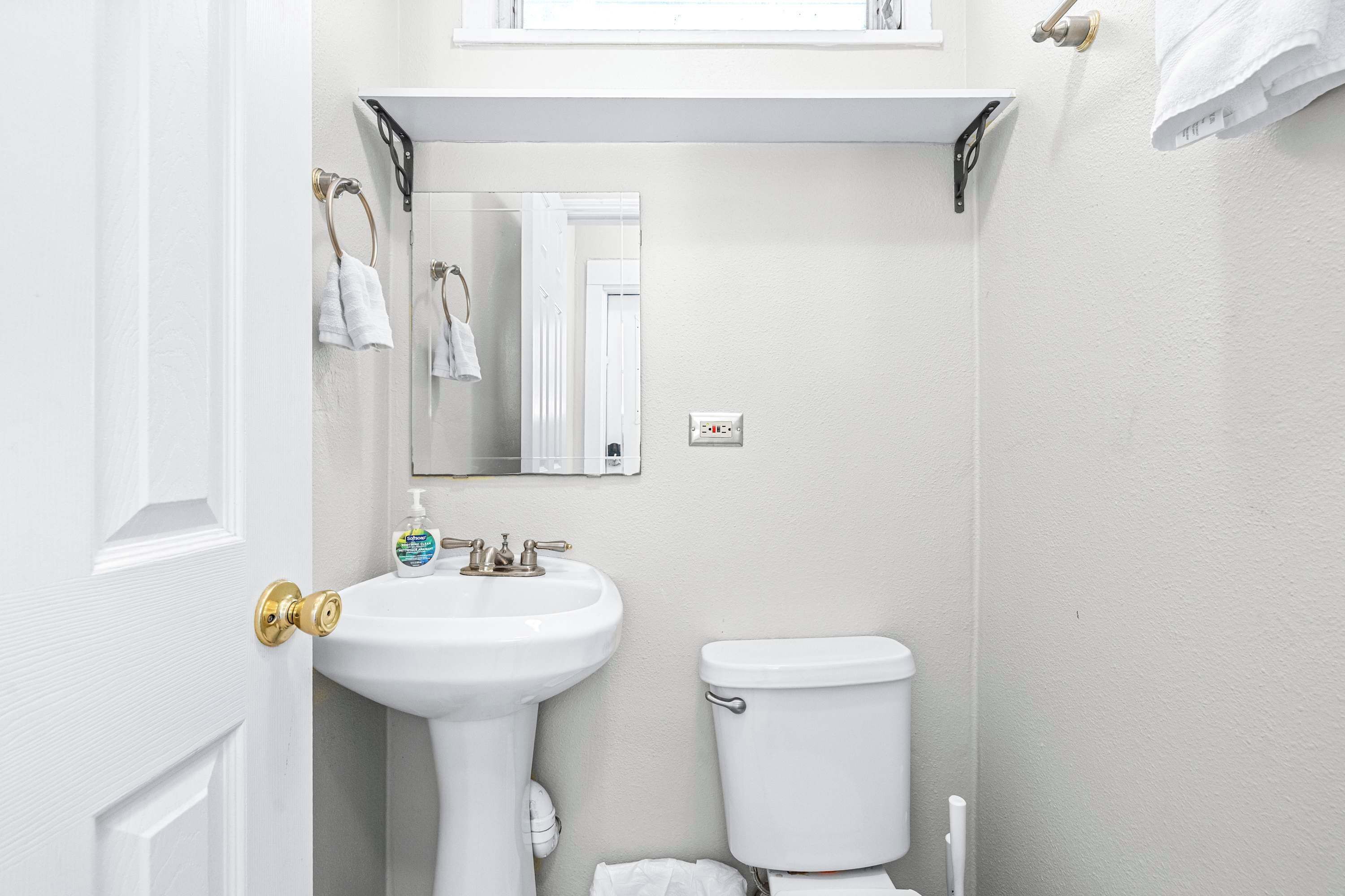 A bathroom with a white sink, toilet, and a mirror above the sink.