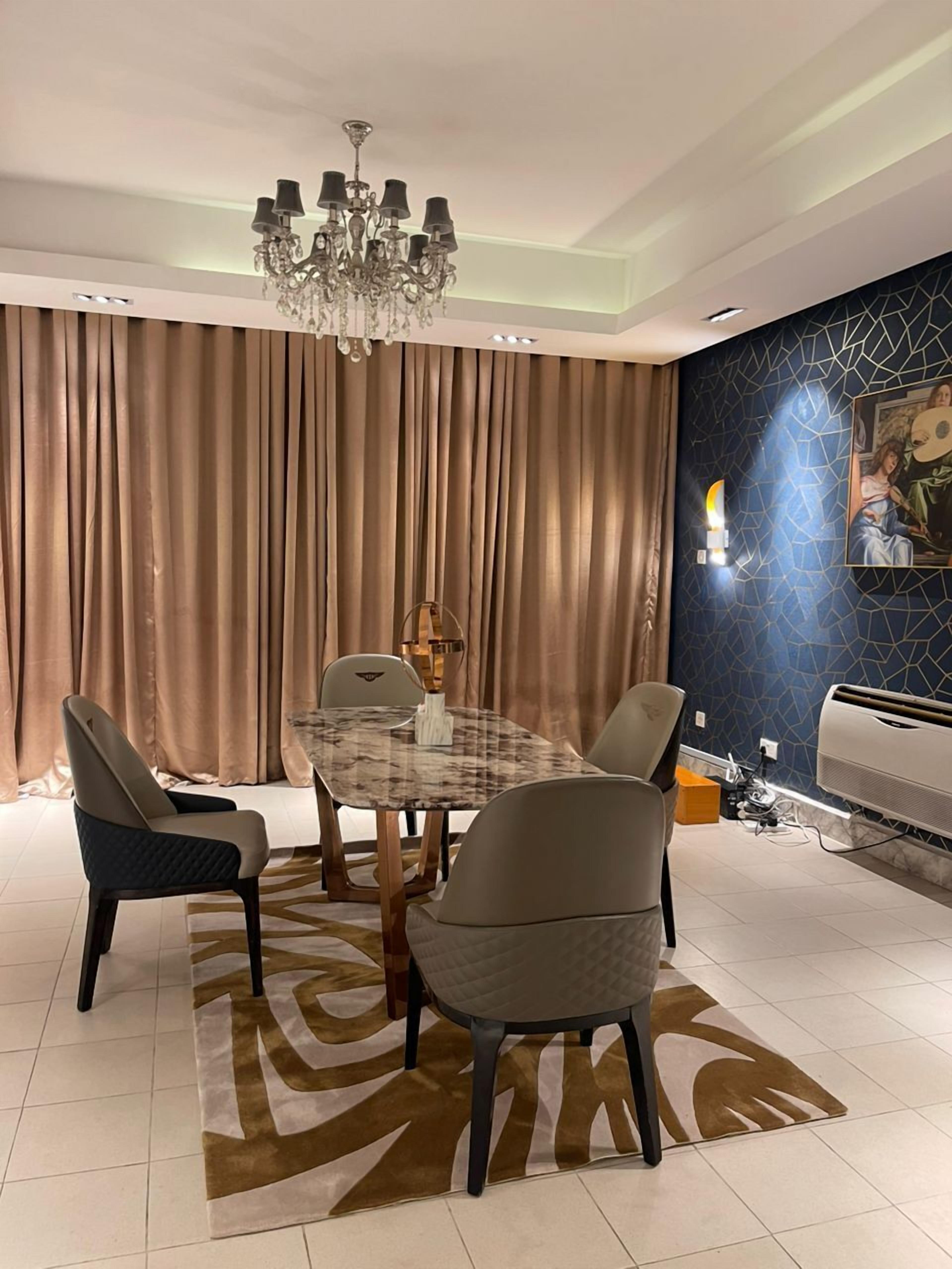 A dining area with a chandelier, a table, chairs, and a patterned rug.