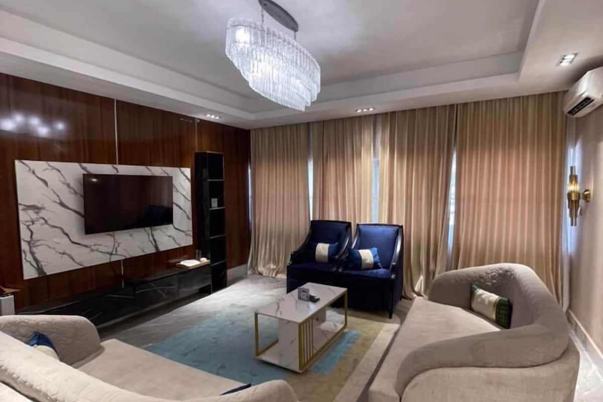 A modern living room with a TV, two sofas, a coffee table, and a chandelier.
