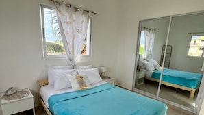 A bedroom with a bed, a nightstand, a window with curtains, and a mirror. - Villa Sol Appartements Punta Canada (Punta Cana)