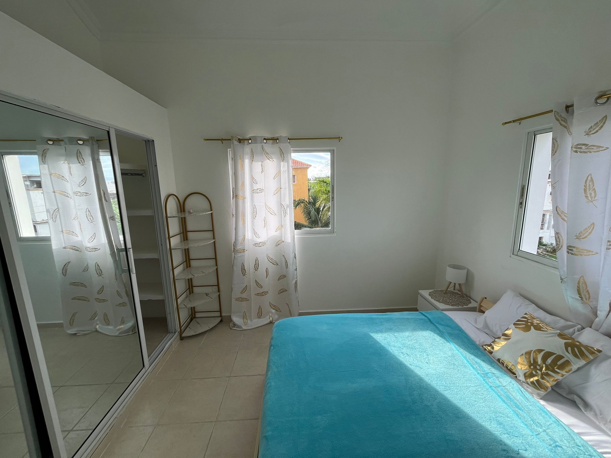 A bedroom with a bed, a window, a wardrobe, and a shelf unit.