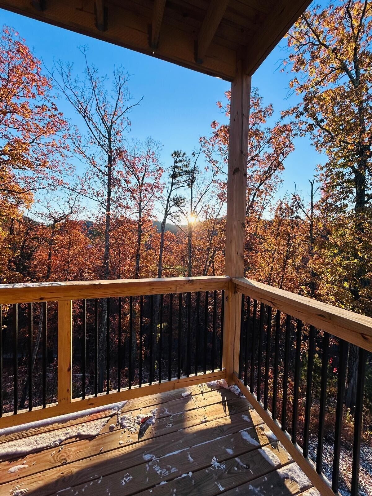 Um deck de madeira com guarda-corpo, vista para uma floresta com folhagem de outono.