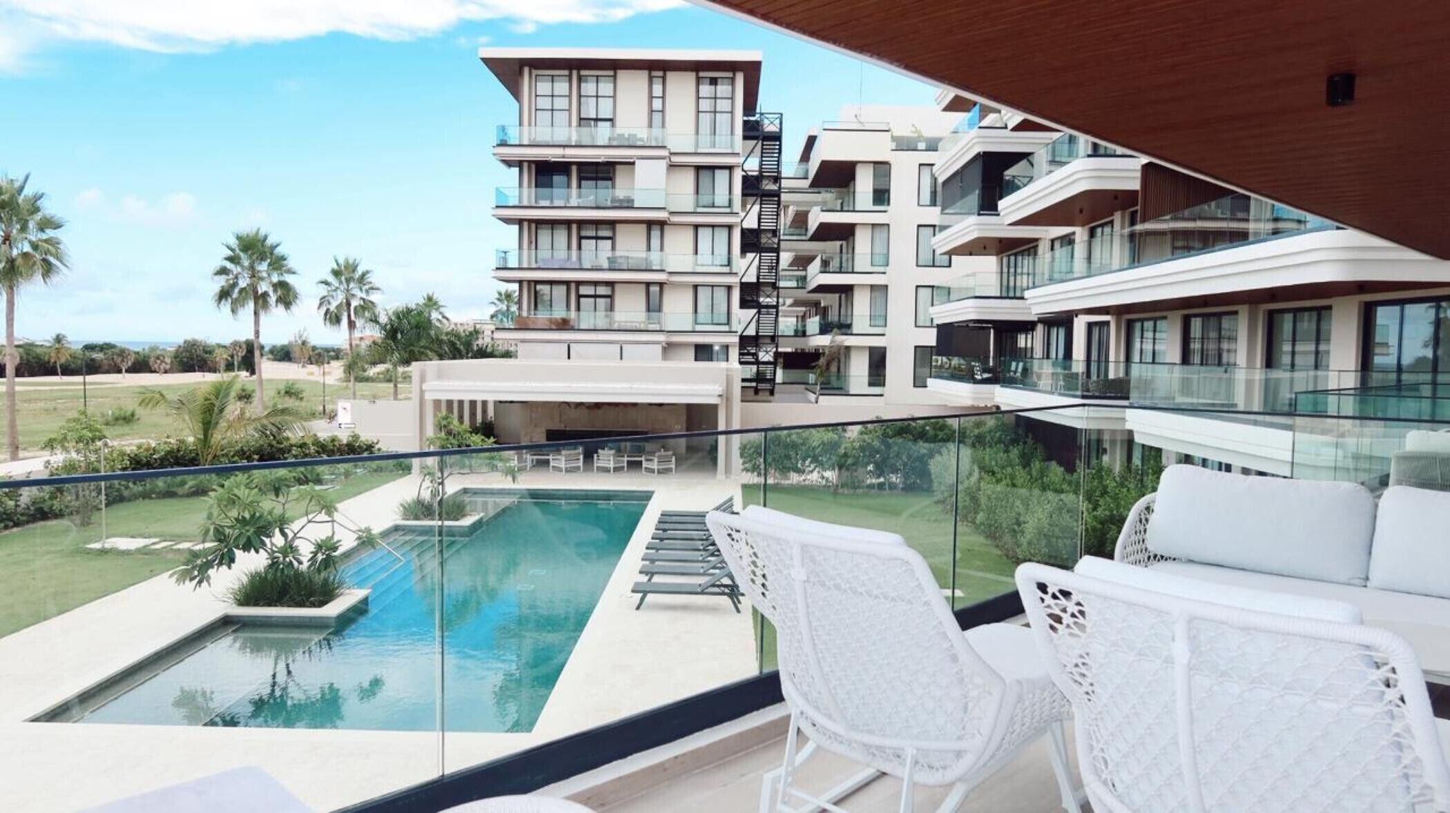 A modern hotel with a rooftop pool, outdoor seating, and a view of the surrounding landscape.
