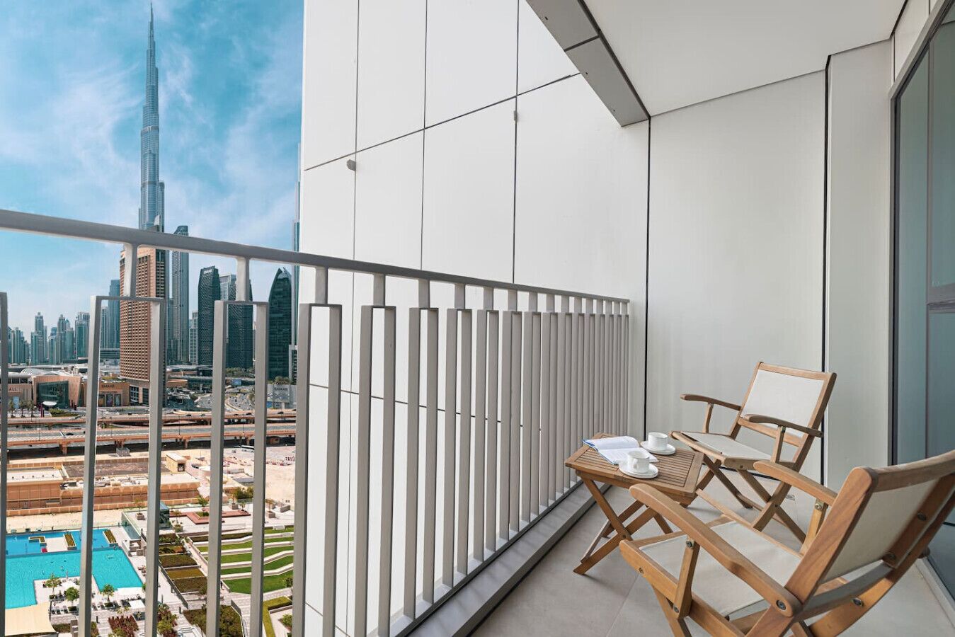 A balcony with a view of the Burj Khalifa and a pool area.