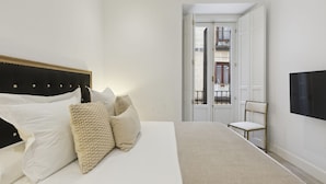 Une chambre à coucher avec un lit, des oreillers, une chaise et un téléviseur.