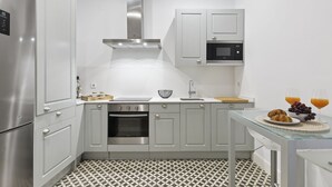 Une cuisine moderne dotée d’appareils électroménagers en acier inoxydable, de meubles blancs et d’un sol à motifs.
