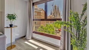 Ein Zimmer mit einem großen Fenster, einem Topfpflanzen und einem kleinen runden Tisch.