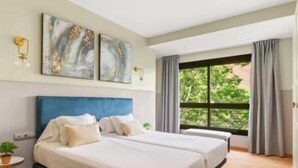 Ein modernes Hotelzimmer mit zwei Betten, einem großen Fenster mit Vorhängen und abstrakter Wandkunst.