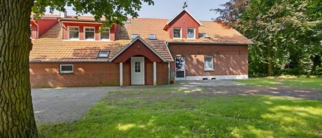 A red-brick house with a sloped roof, a front door, and a small porch.