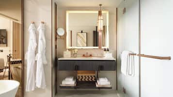 A modern bathroom with a large mirror, a vanity with a towel rack, and a bathtub.