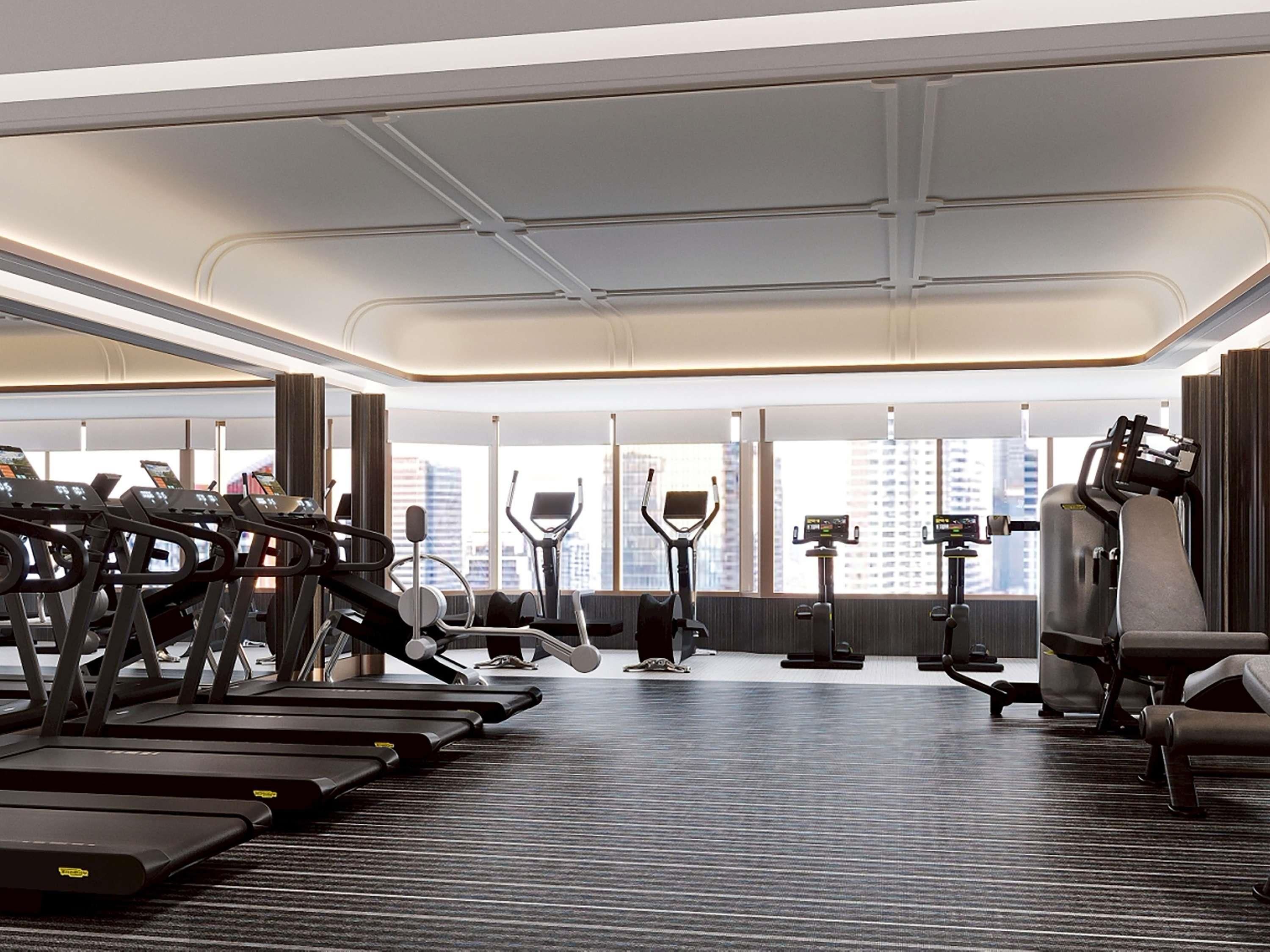 Un gimnasio moderno con cintas de correr, elípticas y equipo de pesas.