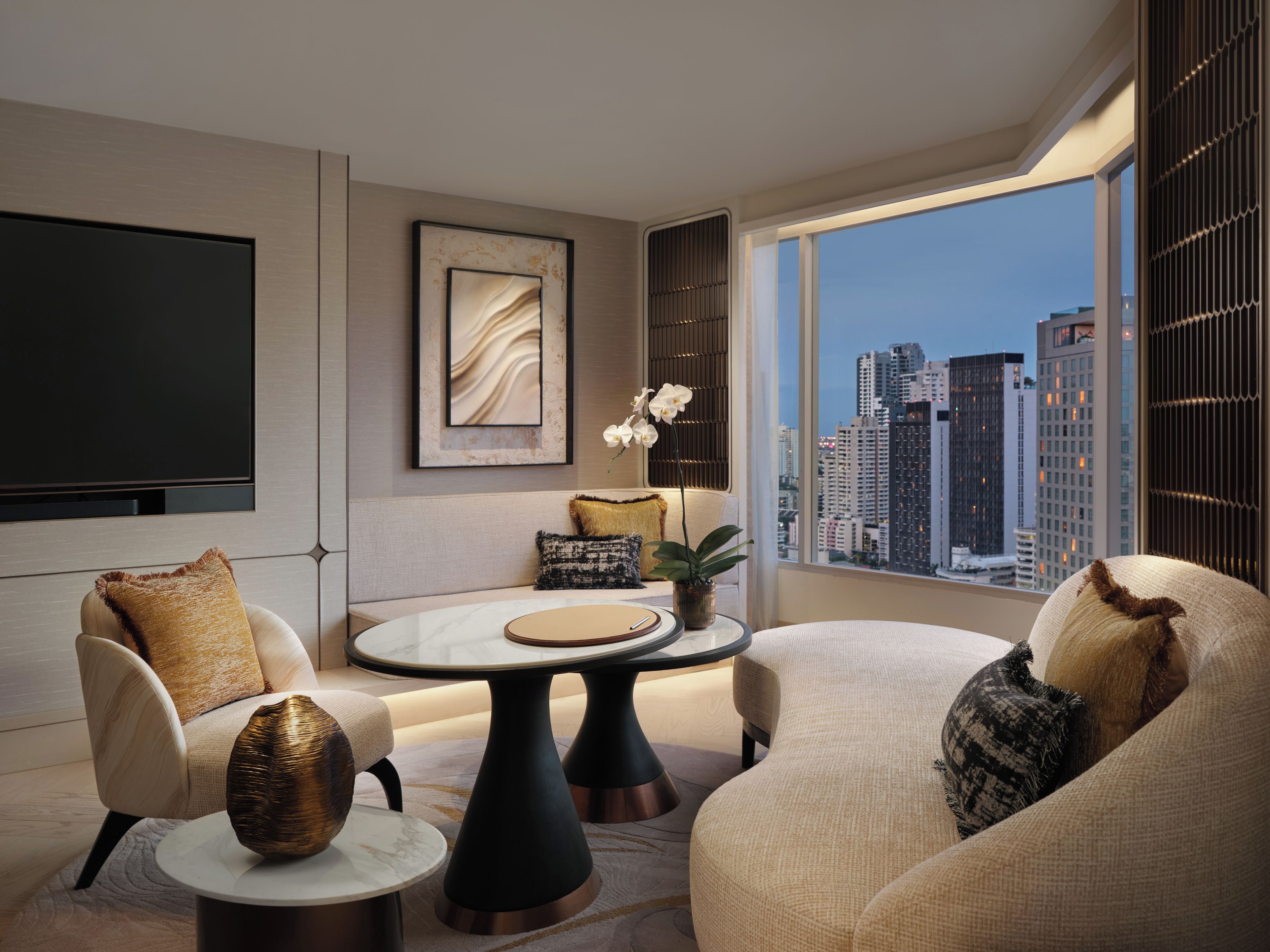 A modern living room with a city view, a flat-screen TV, and a round coffee table.