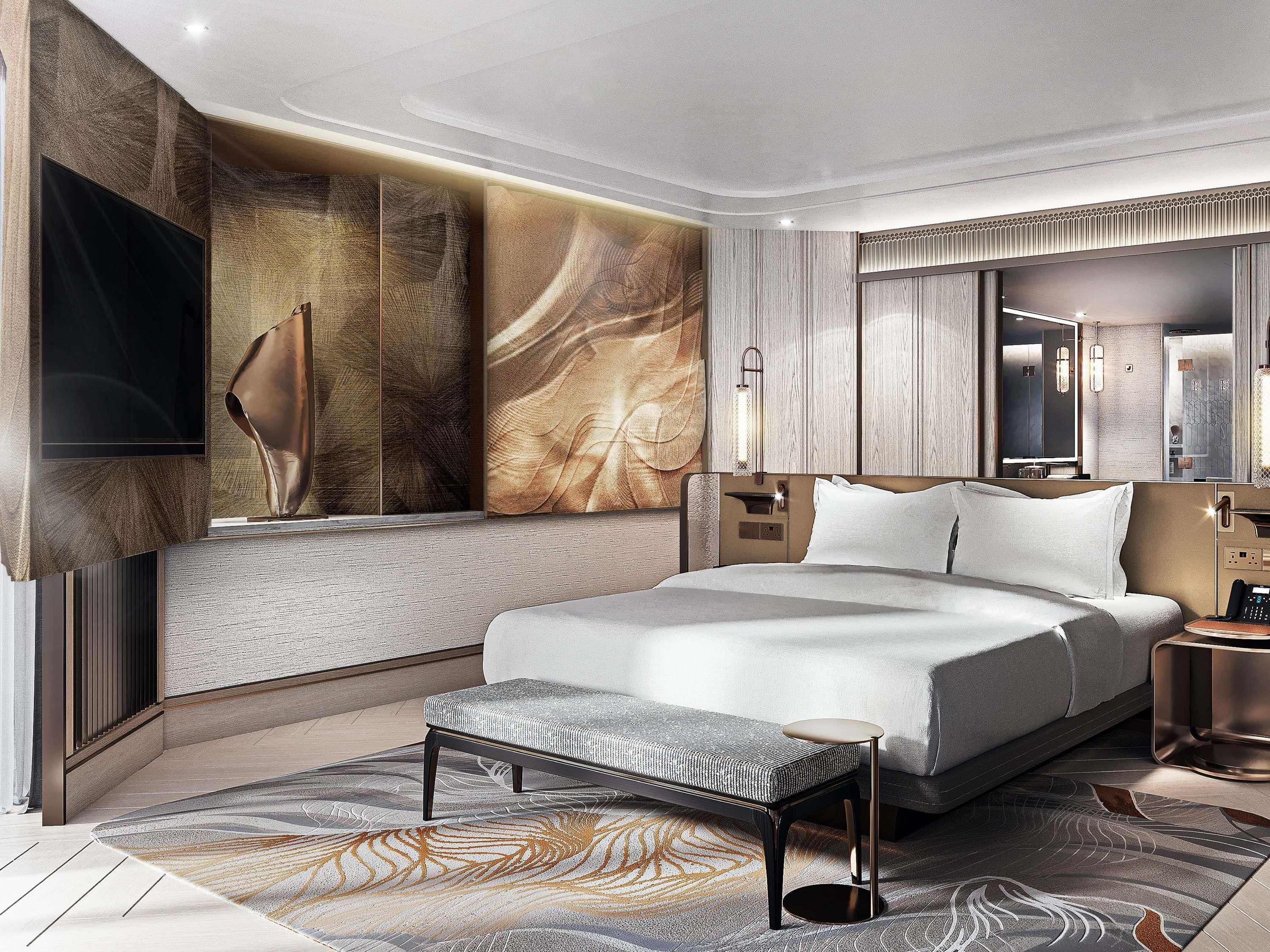 A modern hotel room with a large bed, a flat-screen TV, a bedside table, and a seating area with a bench.