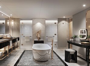 Un baño moderno con una bañera grande, un tocador con espejo y una alfombra en el suelo.