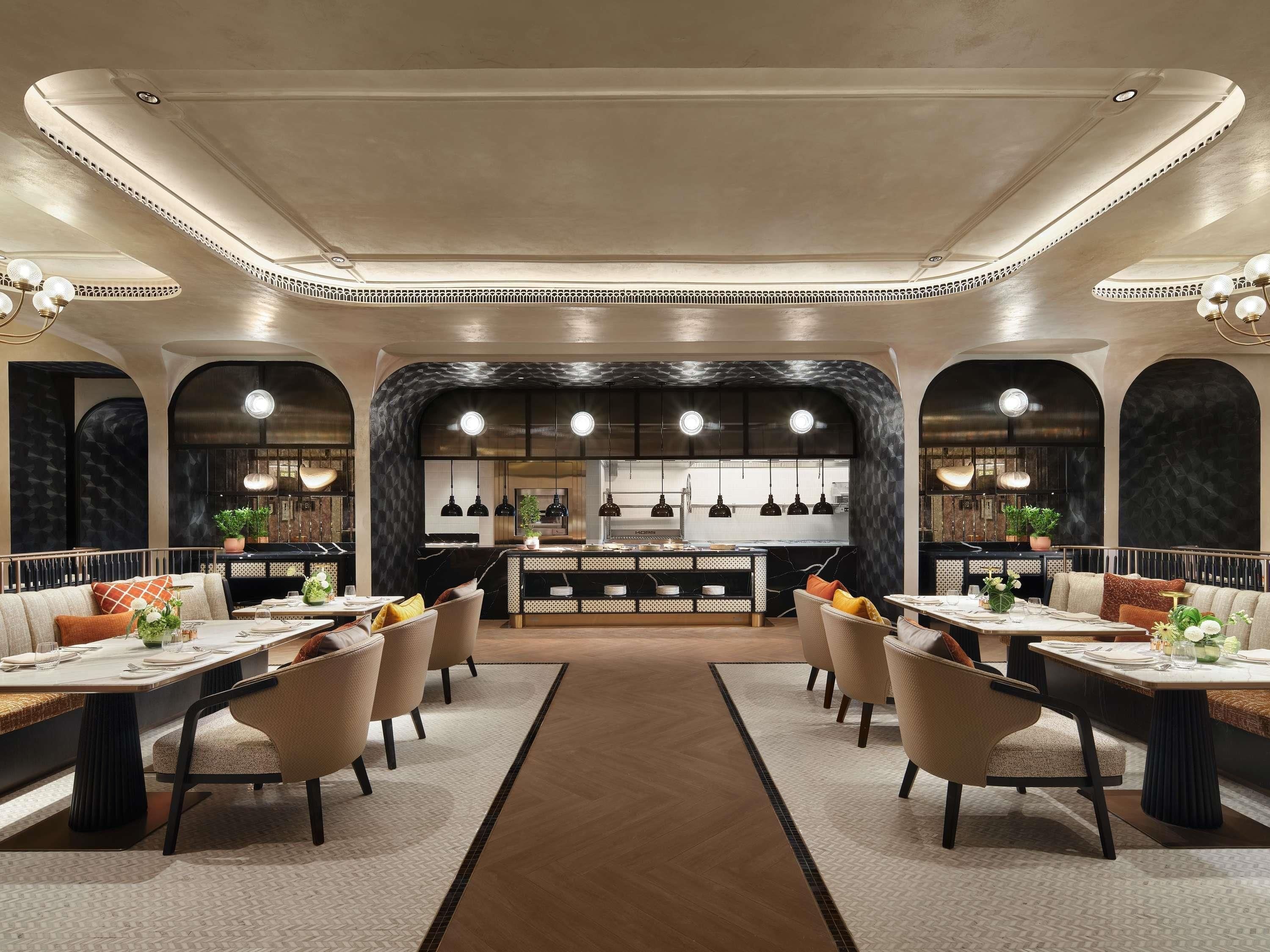 A modern restaurant with a central bar, high ceiling, and symmetrical seating arrangement.