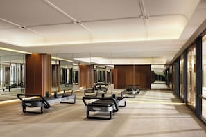 Een moderne hotel lobby met een centraal zitgedeelte, grote spiegels en een lange gang.