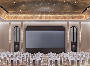 Een feestzaal met ronde tafels voor evenementen, een groot scherm en een plafondontwerp met sterren.