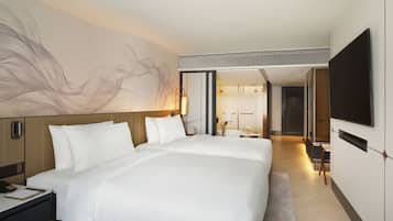 A modern hotel room with a large bed, bedside tables, a desk, a flat-screen TV, and a large abstract painting on the wall.