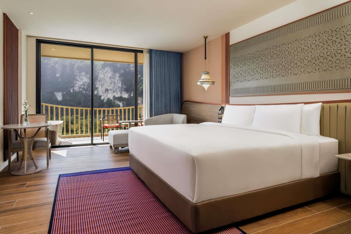 Une chambre d’hôtel dotée d’un grand lit, d’un balcon avec vue, d’un coin repas et d’un mur décoratif.
