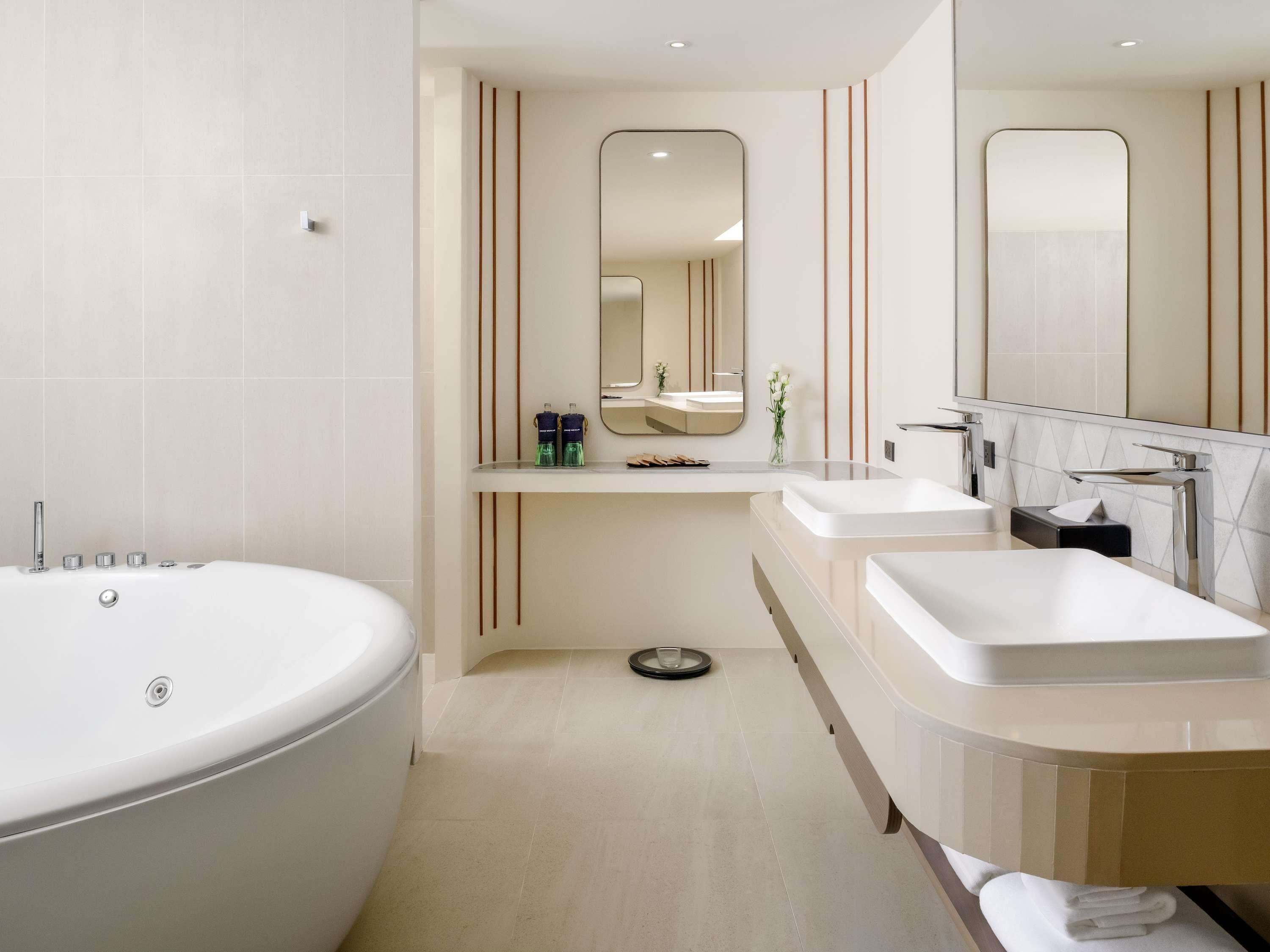 A modern bathroom with a large bathtub, two sinks, and a mirror.